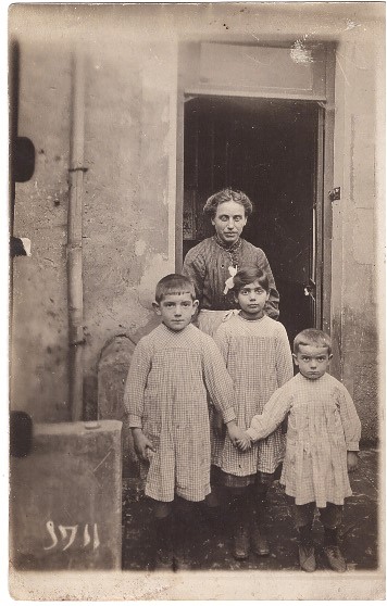 Mère et ses trois enfants à l'entrée de leur maison