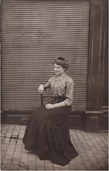 Femme assise devant le rideau de fer baissé de son commerce (?)