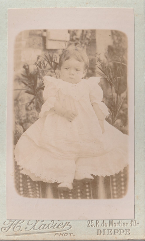 Bébé en robe blanche posant dans un jardin