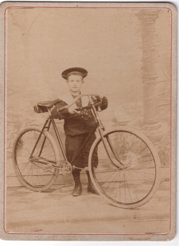 Garçon en tenue de marin posant avec une bicylette