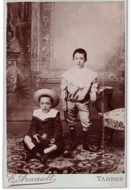 Deux garçons, dont l'un tient un ballon en cuir,  posant en atelier