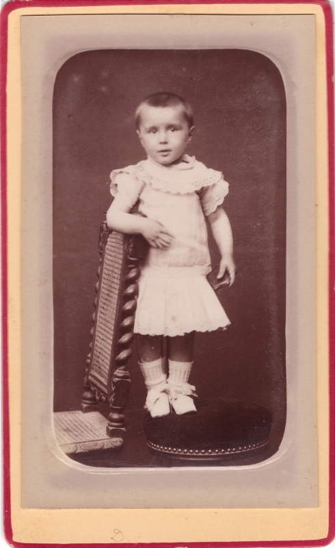Enfant en robe debout sur un tabouret