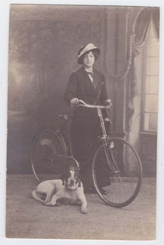 Femme posant avec sa bicyclette et son chien