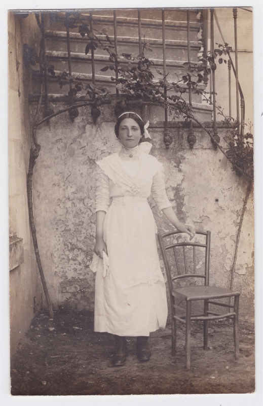 Jeune femme en blanc debout près d'une chaise