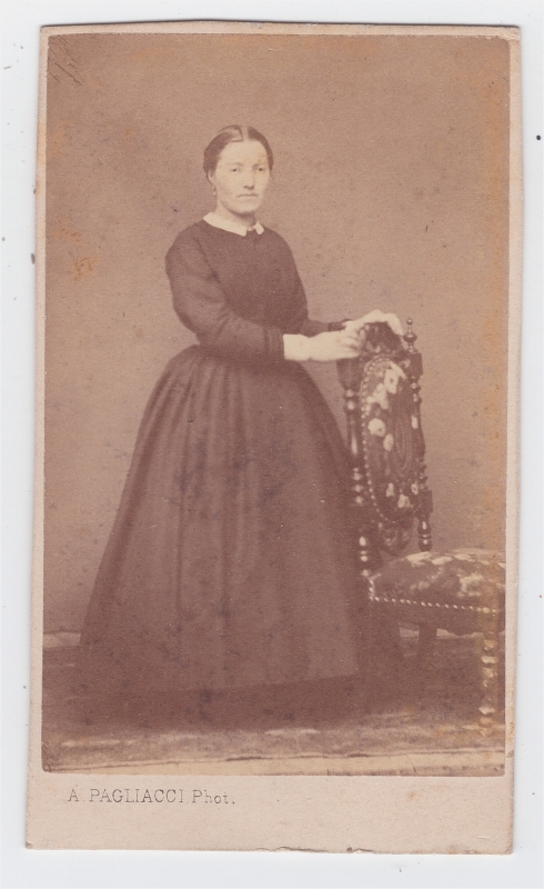 Jeune femme debout, les mains posées sur le dossier d'une chaise