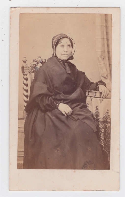 Femme âgée, une main posée sur un album de photographies.