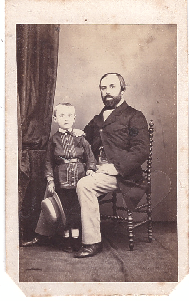 Homme assis à côté de son fils qui tient un chapeau de paille