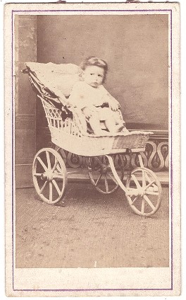 Bébé dans une poussette tricycle en osier