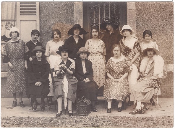 13 jeunes femmes posant devant l'entrée d'une maison