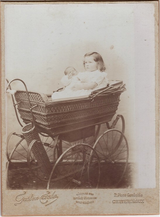 Fillette et un bébé dans un landau en osier.