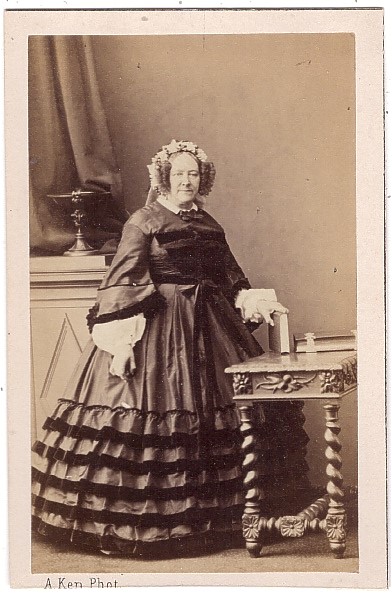 Femme debout près d'une table sur laquelle sont posés des albums de photographies