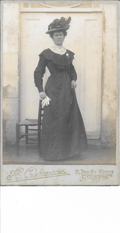 Femme en noir posant devant la porte blanche d'une maison