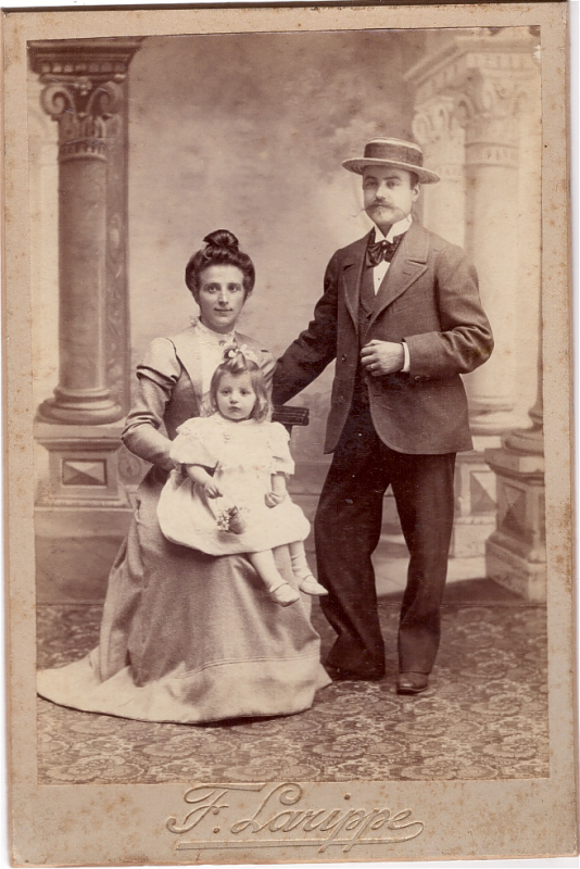 Jeune femme posant à côté de son mari avec sa petite fille sur ses genoux.