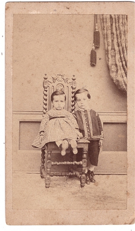 Deux enfants, le plus jeune assis sur une chaise