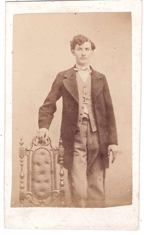 Jeune homme posant debout près d'une chaise