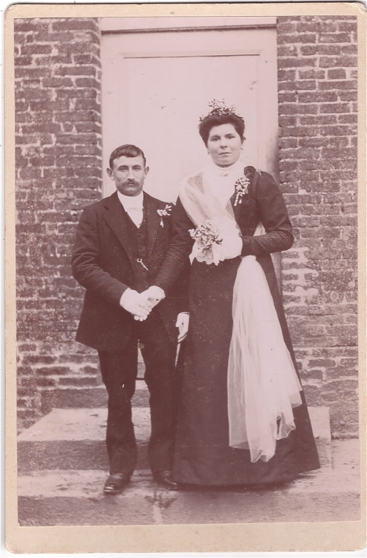 Mariés posant devant une maison
