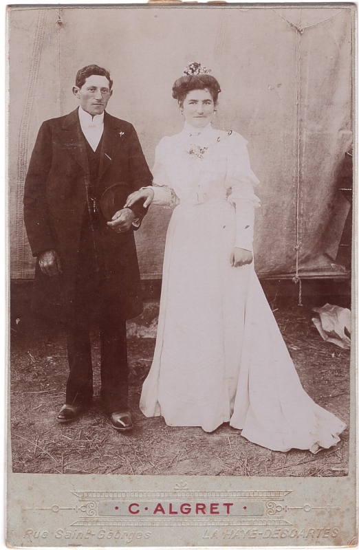 Mariés posant en extérieur devant une toile blanche