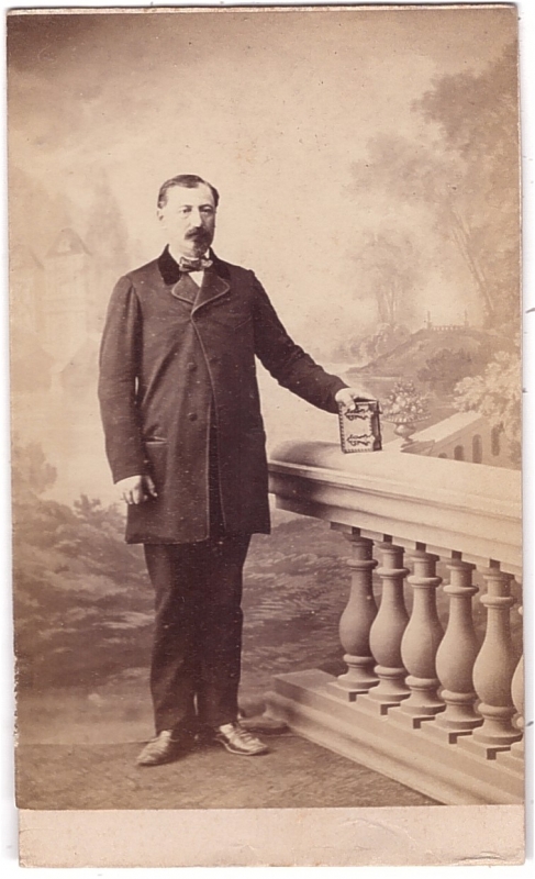 Homme debout une main posée sur un album de photographies