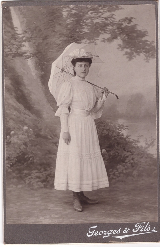 Jeune fille, tout de blanc vêtue, qui pose avec son ombrelle