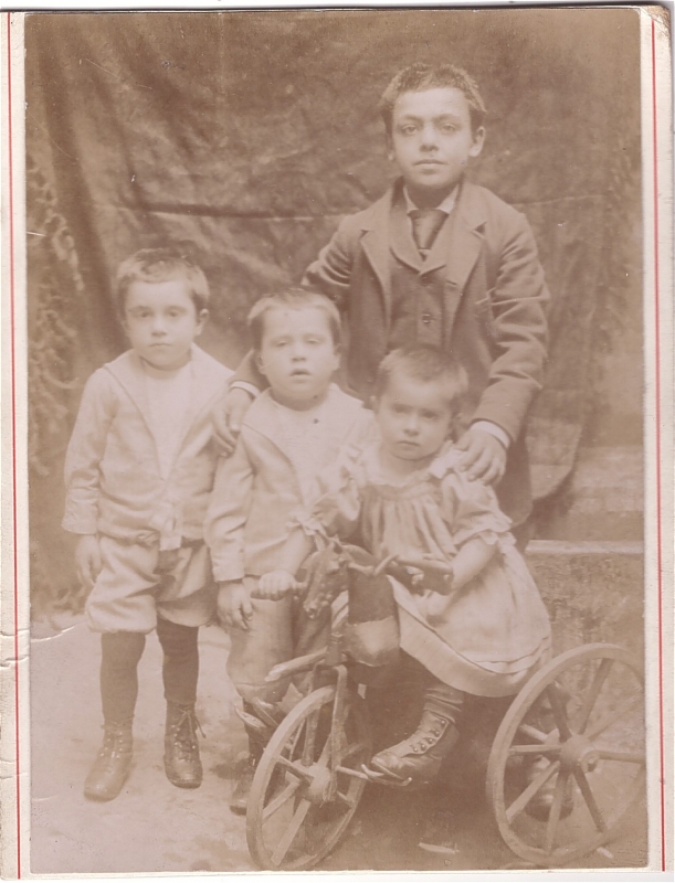 Quatre l'enfants, le plus jeune sur un tricycle.