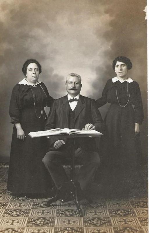 Un homme assis encadré par deux femmes debout