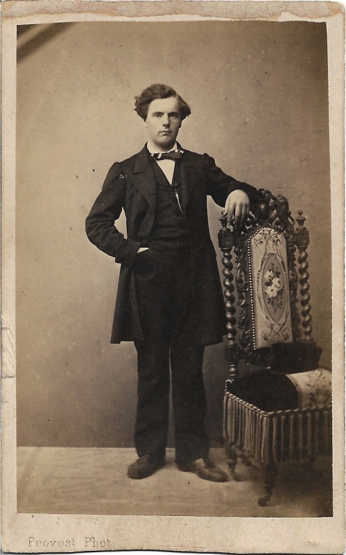 Jeune homme debout à côté de la chaise où il a posé sa casquette