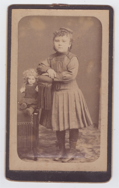 Petite fille posant à côté de  sa poupée
