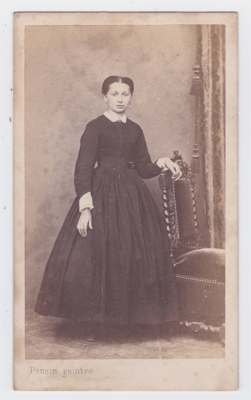 Jeune femme en robe noire debout près d'une chaise