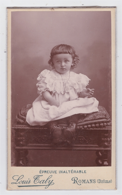Bambin en robe blanche assis sur un coussin